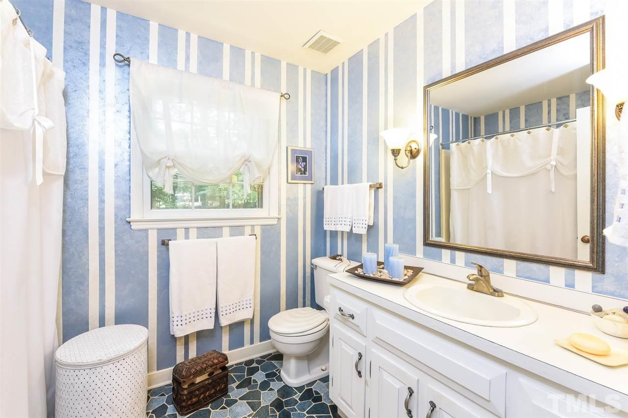 9716 Rock Creek Road Raleigh, NC 27613 - Photo 22 of 25 a bathroom with a granite countertop sink toilet a mirror and a shower