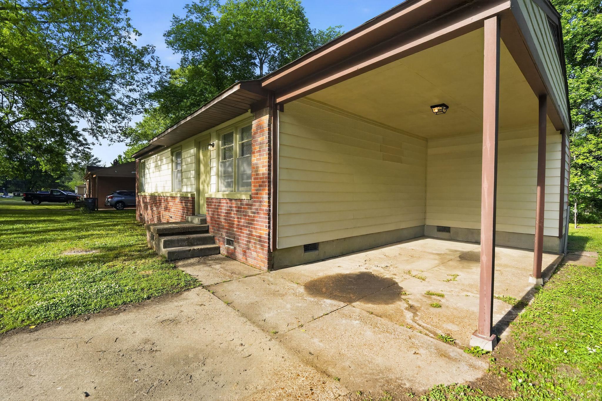 4955 Stacey Road Memphis, TN 38109 - Photo 5 of 35 Exterior featuring a covered carport, brick facade, siding, and mature trees
