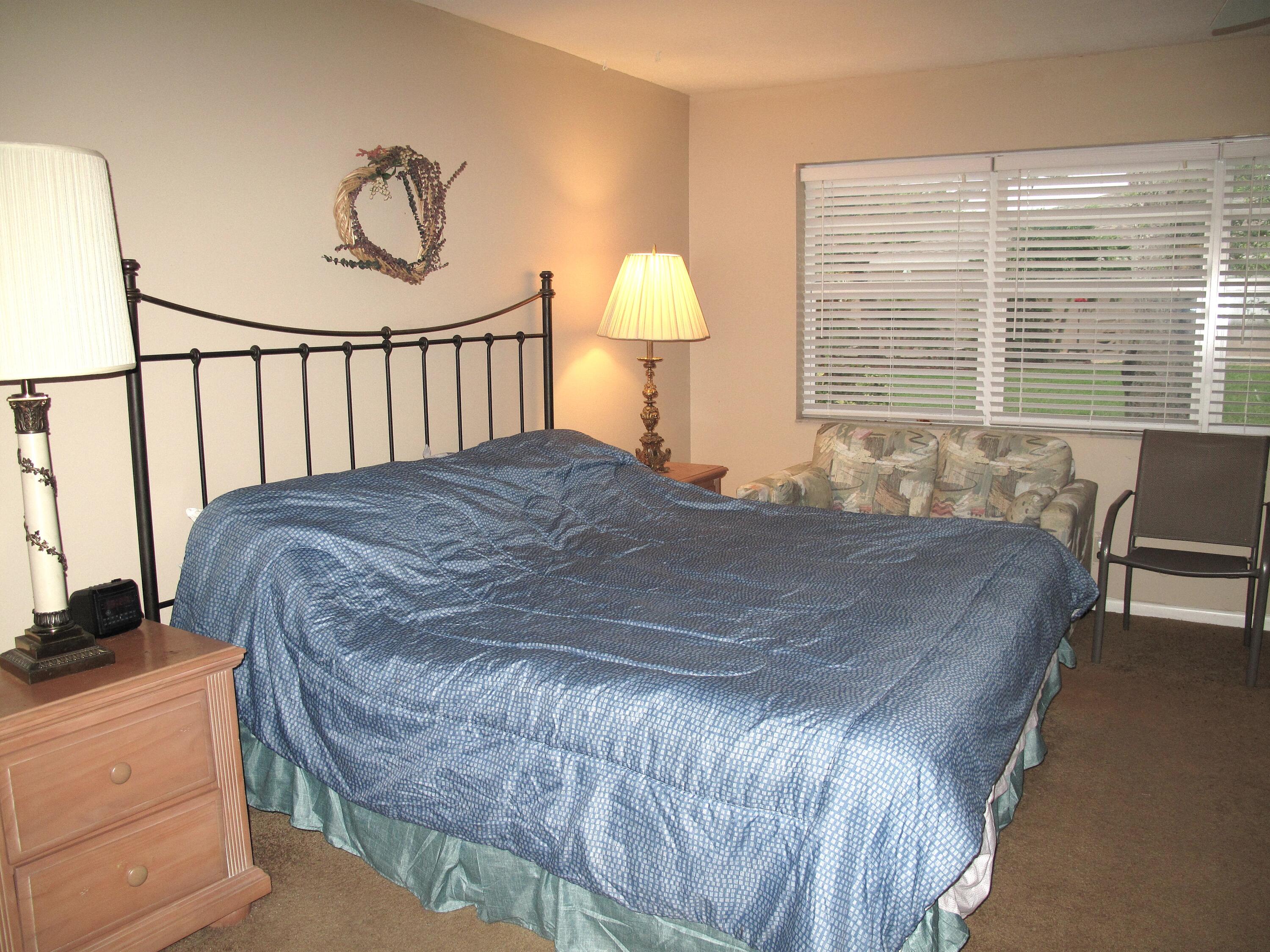 1315 High Point Way Southeast, Unit B Delray Beach, FL 33445 - Photo 17 of 41 a bed sitting in a bedroom next to a window