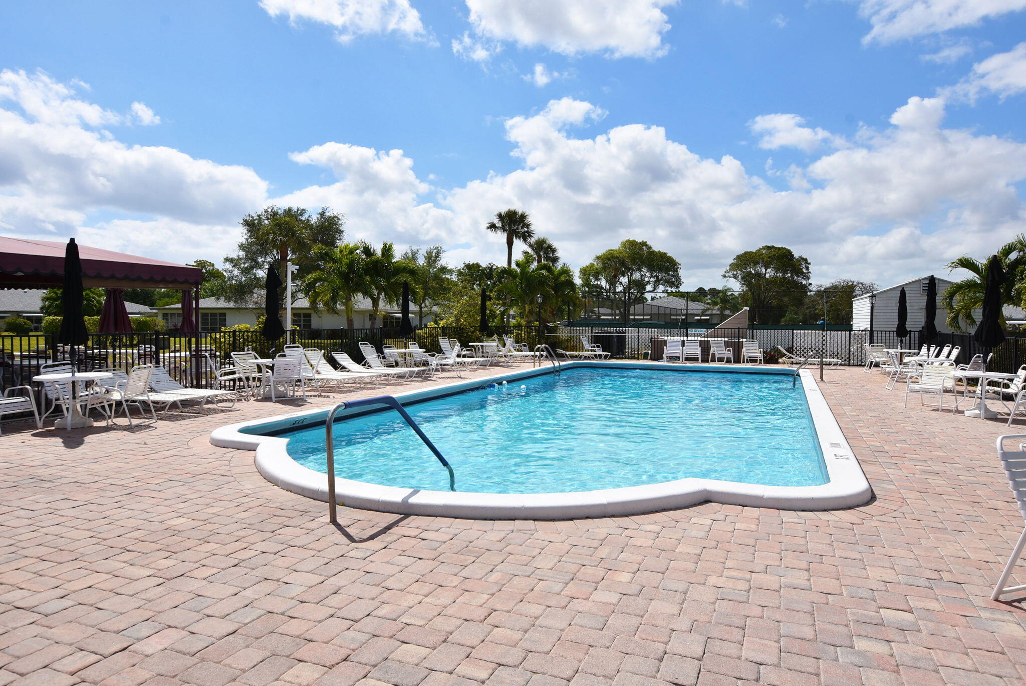 1315 High Point Way Southeast, Unit B Delray Beach, FL 33445 - Photo 34 of 41 a view of a swimming pool with a lounge chair and tables