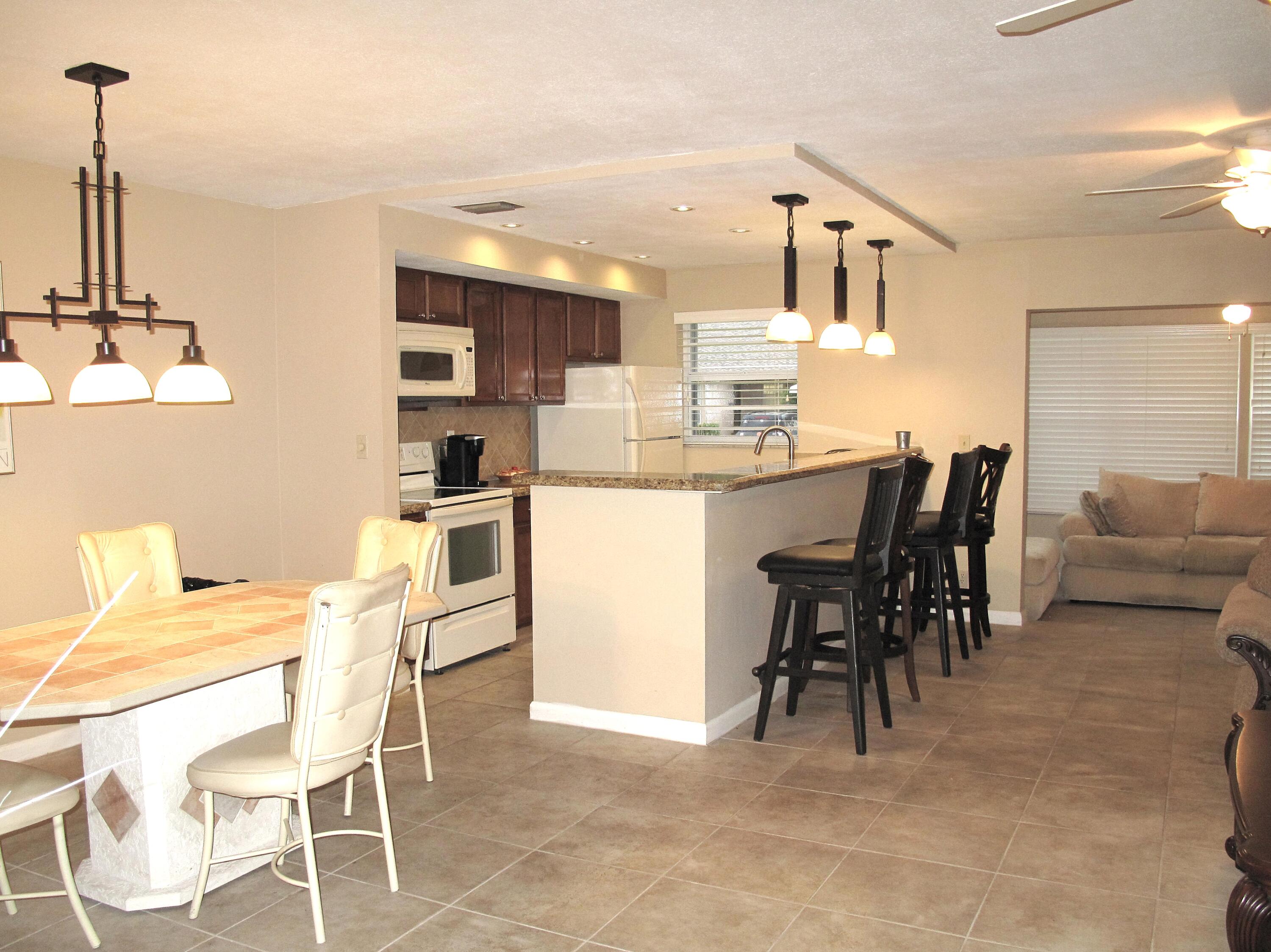 1315 High Point Way Southeast, Unit B Delray Beach, FL 33445 - Photo 4 of 41 a kitchen with kitchen island a dining table and chairs