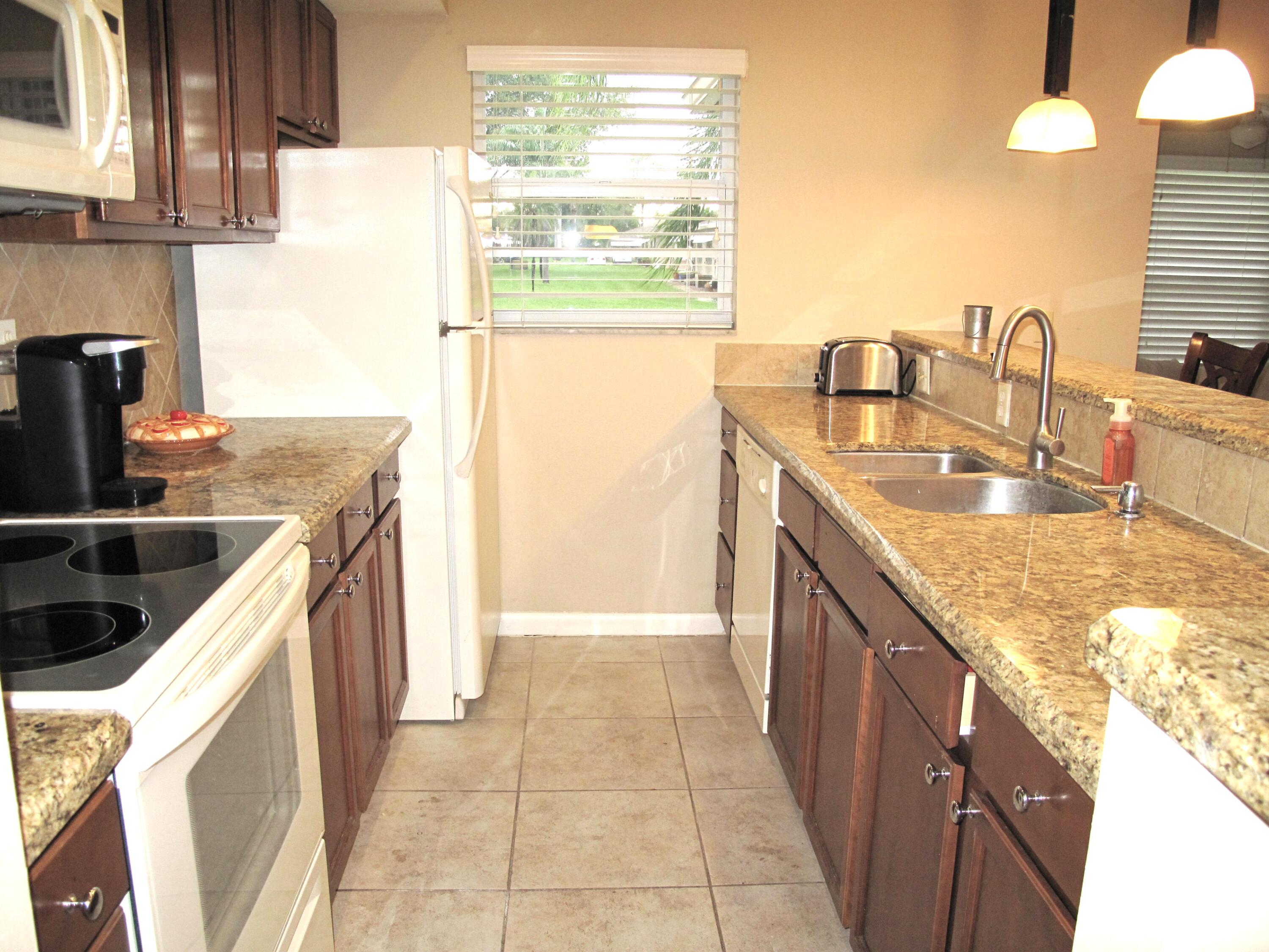 1315 High Point Way Southeast, Unit B Delray Beach, FL 33445 - Photo 5 of 41 a kitchen with granite countertop a sink a stove and a wooden floors