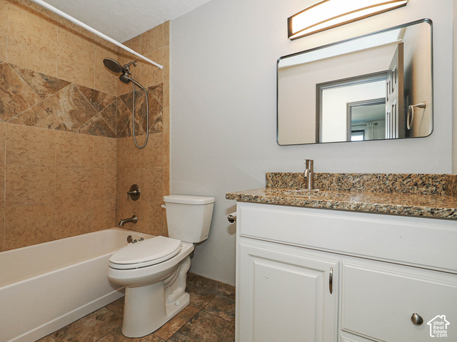 3308 Willow Ridge Road Salt Lake City, UT 84121 - Photo 47 of 59 Tile flooring, built-in tub with tile surround, white vanity cabinetry with a stone countertop, and an integrated rectangular sink