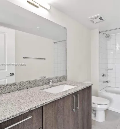 a bathroom with a granite countertop sink a toilet and shower