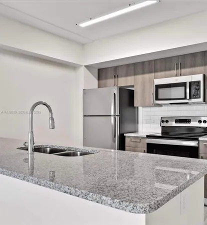 a kitchen with stainless steel appliances granite countertop a sink refrigerator and microwave