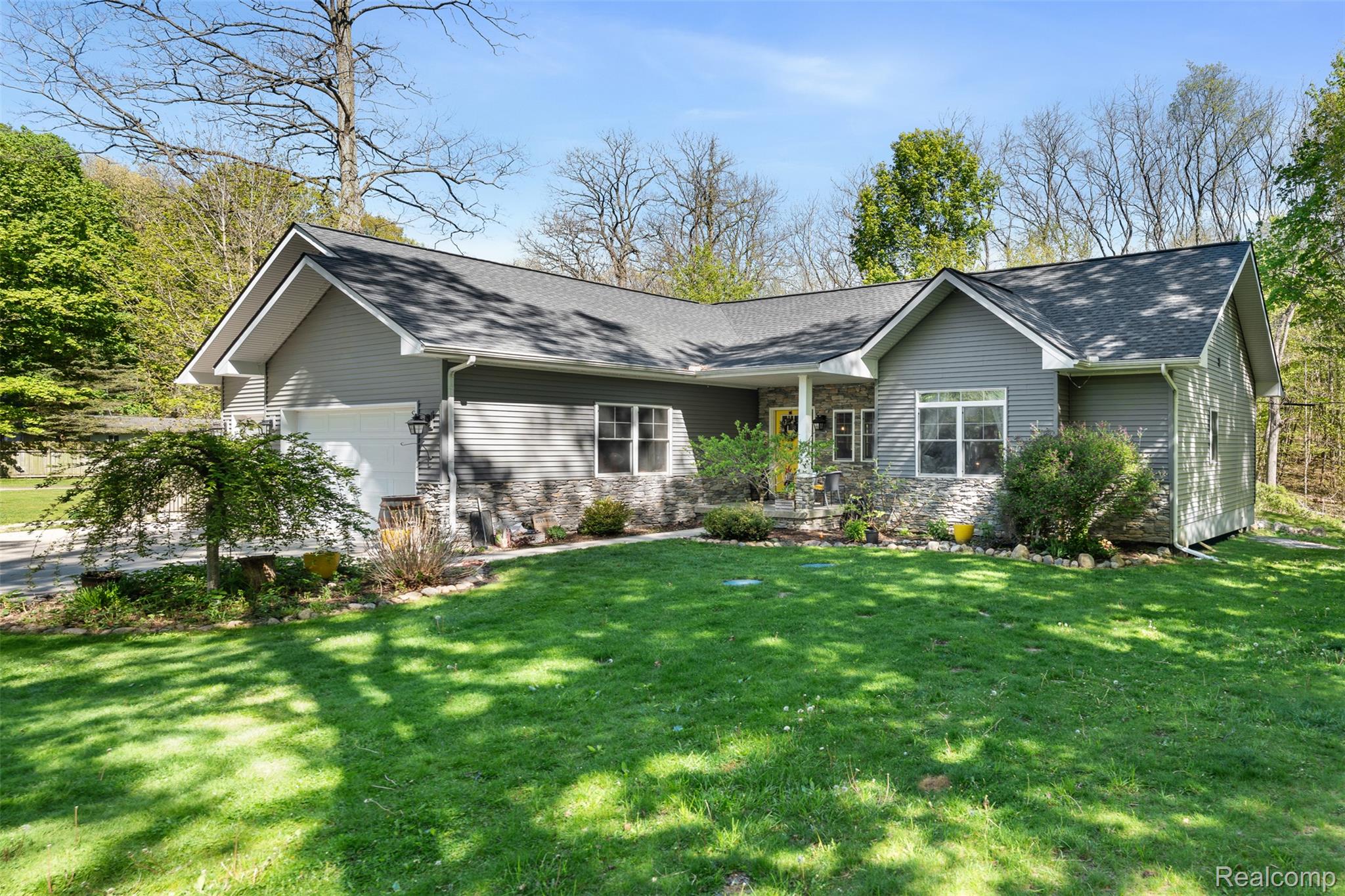View of front of home featuring a garage, a front yard, and a shingled roof