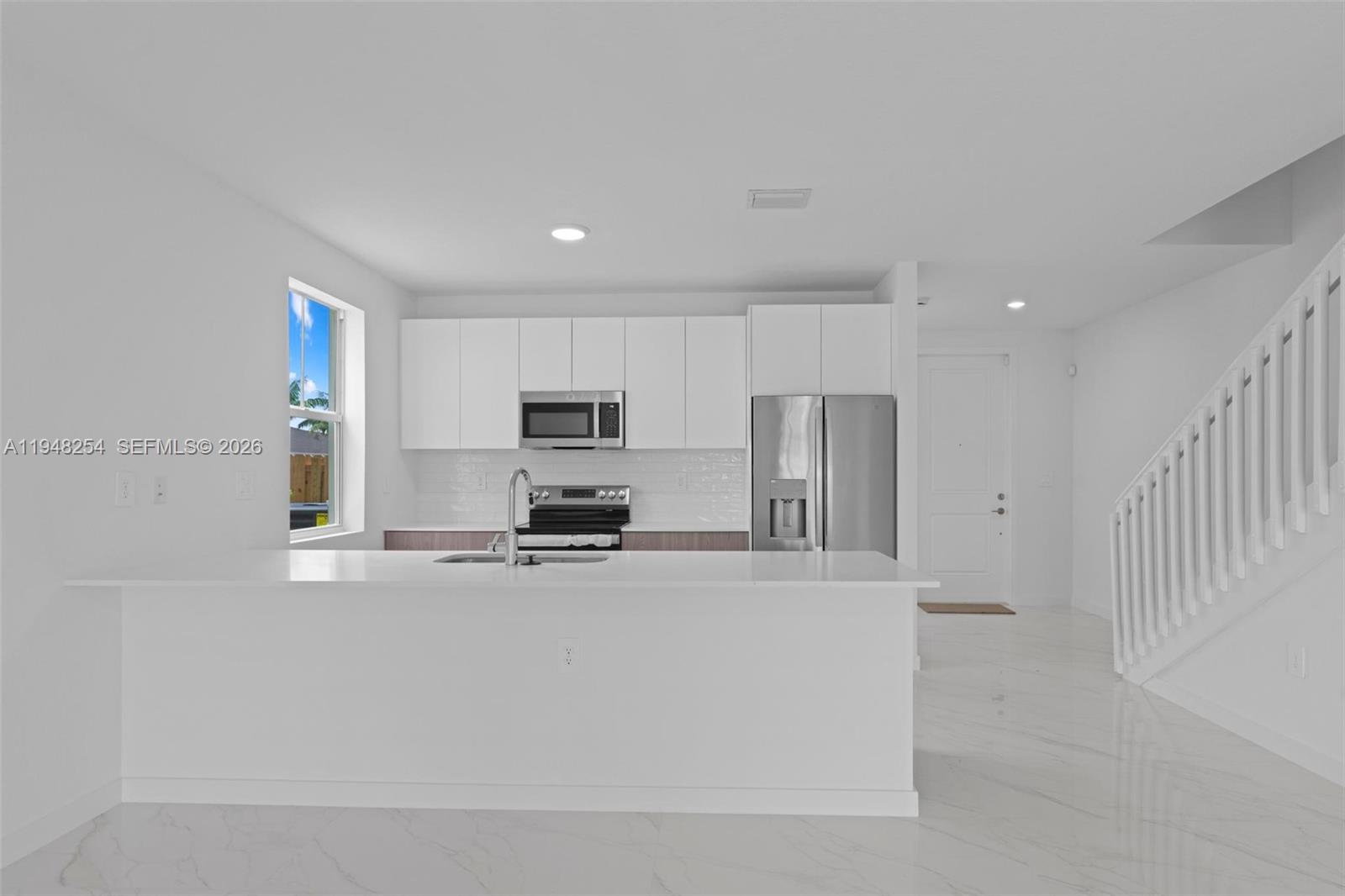 27335 Southwest 133rd Path Homestead, FL 33032 - Photo 32 of 39 a large white kitchen with stainless steel appliances a large counter top and a stove top oven
