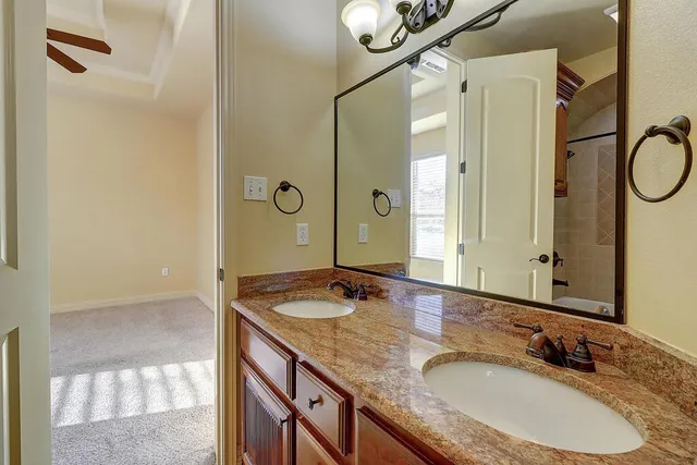 a bathroom with a granite countertop sink a mirror and a shower