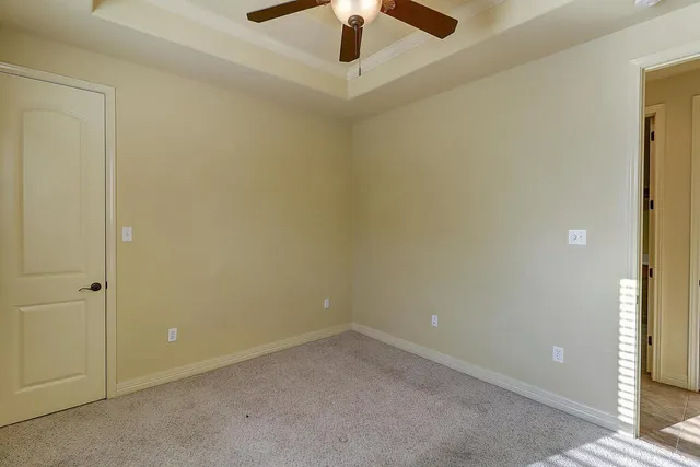an empty room with a ceiling fan and carpet
