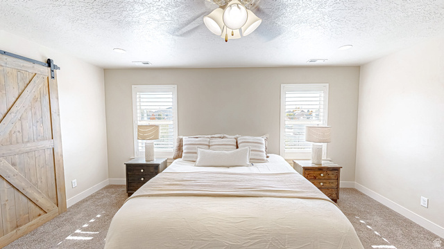 368 East 700 North Springville, UT 84663 - Photo 10 of 55 Bedroom with a barn door, a ceiling fan, light carpet, and a textured ceiling