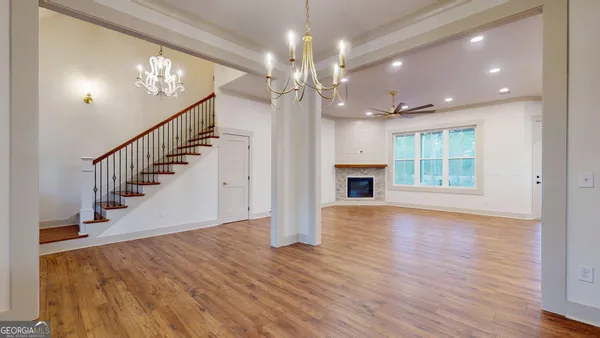 a view of a livingroom with wooden floor a ceiling fan and windows