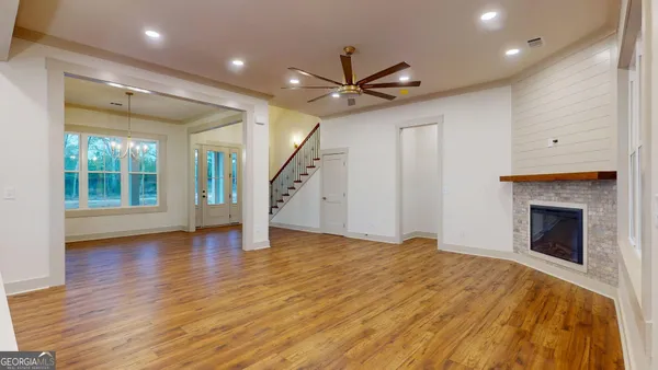 a view of an empty room with wooden floor fireplace and a window