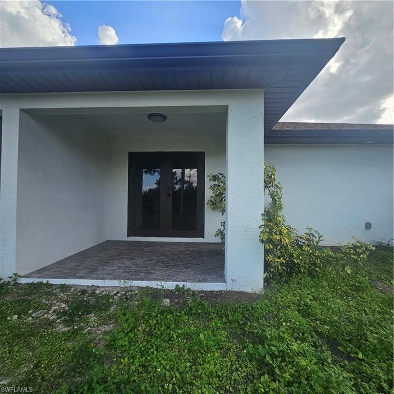 4722 29th Street Southwest Lehigh Acres, FL 33973 - Photo 12 of 12 Property entrance with french doors and stucco siding