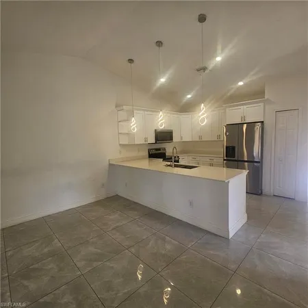 a large kitchen with a refrigerator a stove top oven and a sink