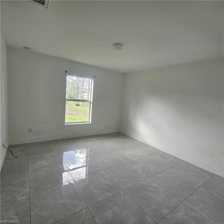4722 29th Street Southwest Lehigh Acres, FL 33973 - Photo 7 of 12 Spare room with baseboards and light tile patterned floors