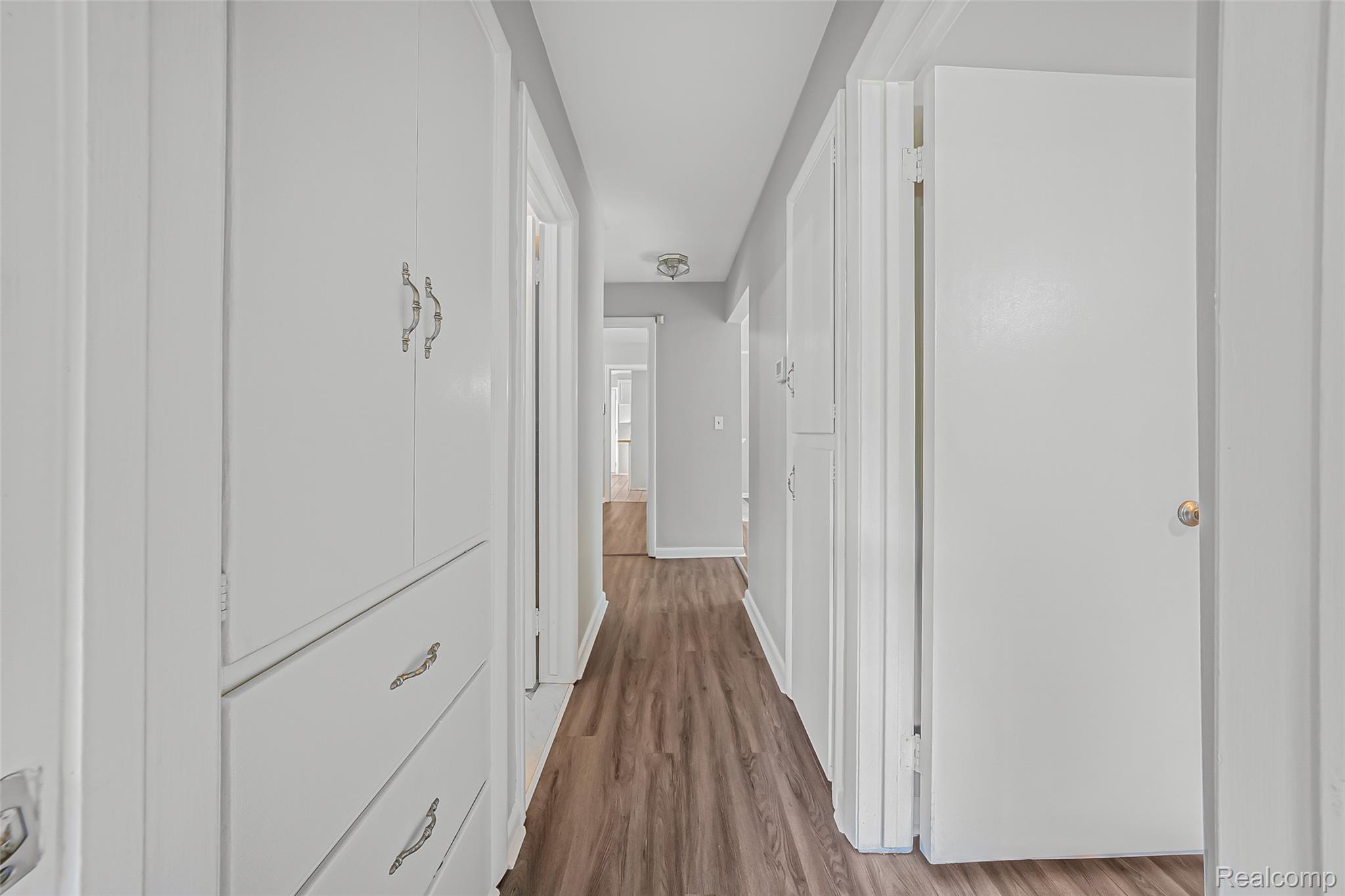 2329 Rutherford Road Bloomfield Hills, MI 48302 - Photo 16 of 46 Hallway featuring wood-finish flooring, white doors, and built-in cabinetry with drawers and decorative hardware
