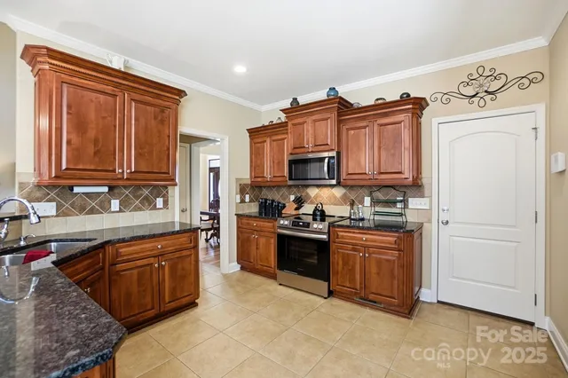 a kitchen with stainless steel appliances granite countertop a stove top oven a sink dishwasher and a refrigerator with wooden cabinets