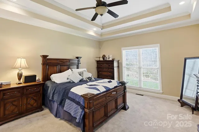 a bedroom with a bed a dresser and a chandelier