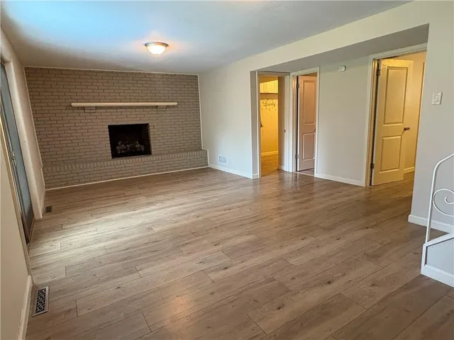 an empty room with wooden floor and a fireplace