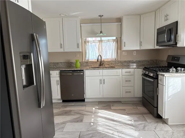 a kitchen with stainless steel appliances granite countertop a stove a refrigerator and a sink