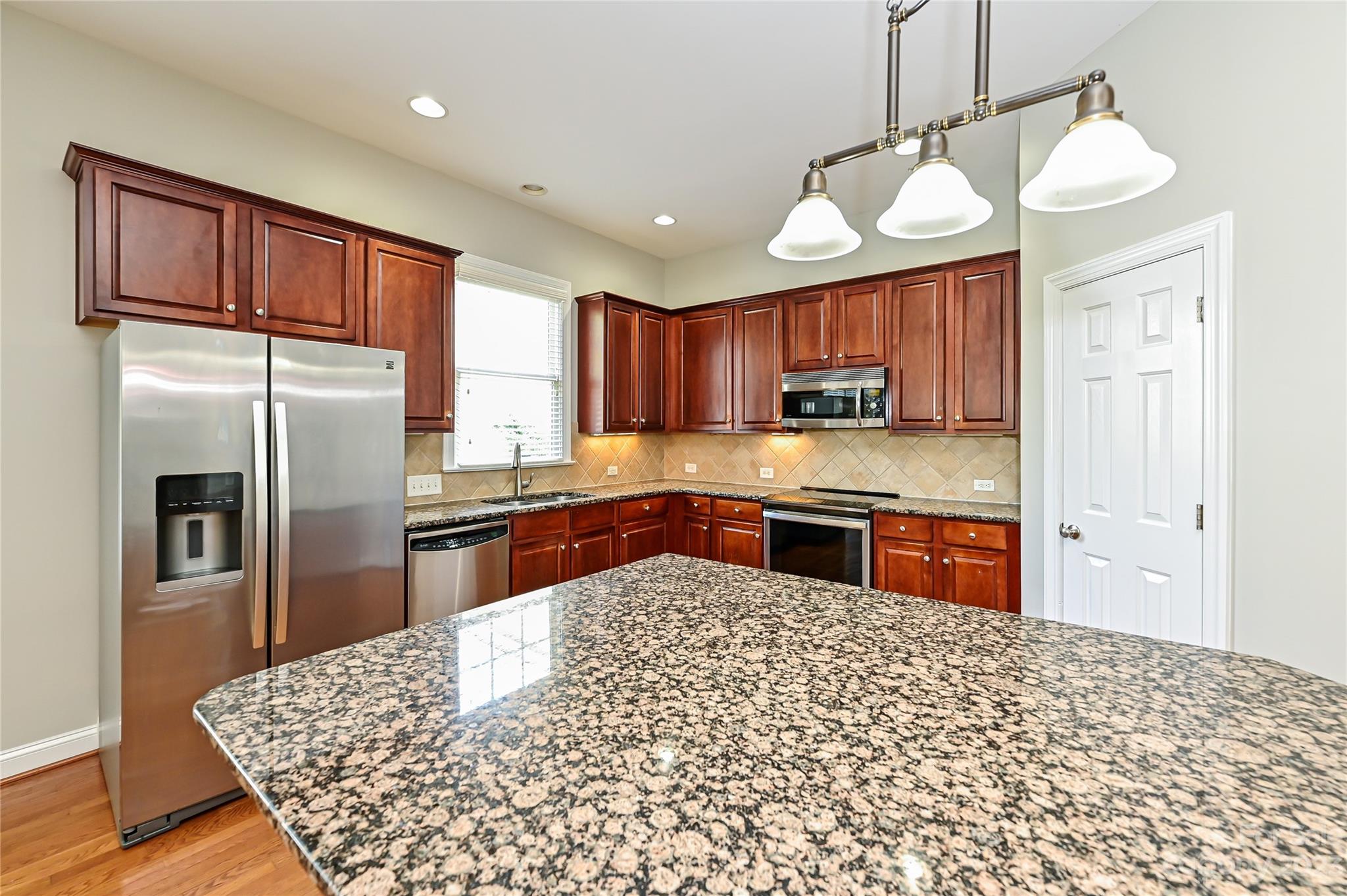 105 Mills Lane Fort Mill, SC 29708 - Photo 12 of 41 a kitchen with stainless steel appliances granite countertop a refrigerator a sink dishwasher a stove with wooden cabinets and floor