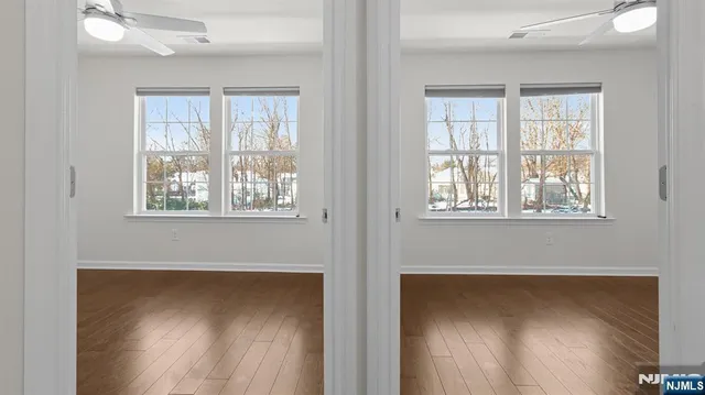 a view of empty room with wooden floor and fan