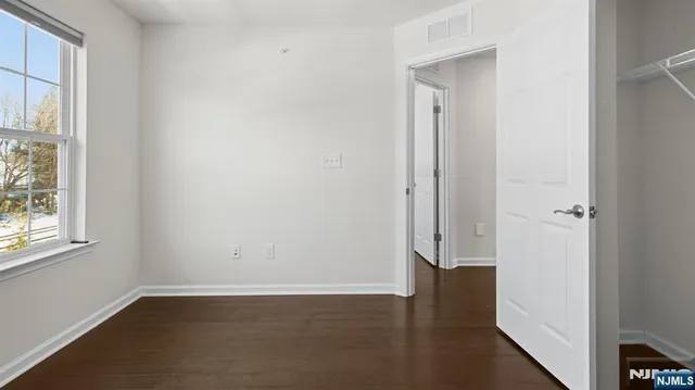 an empty room with wooden floor and windows with curtains