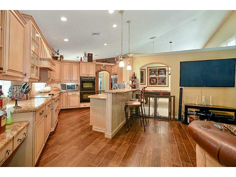 7070 Northwest Turtle Walk Boca Raton, FL 33487 - Photo 3 of 10 a open kitchen with stainless steel appliances kitchen island granite countertop a stove top oven a sink a dining table and chairs with wooden floor