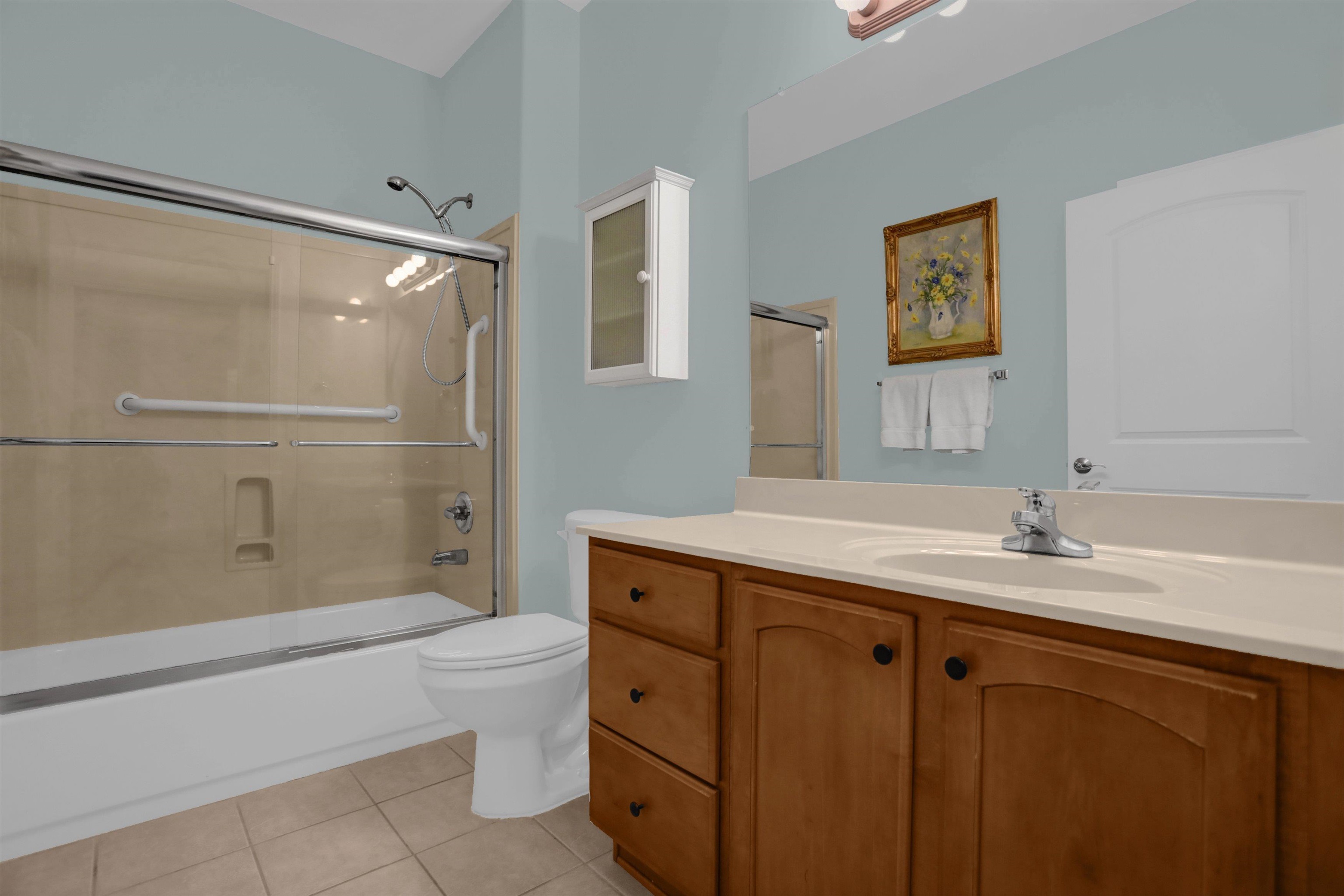 34 Peyton Ridge Drive, Unit 21 Collierville, TN 38017 - Photo 22 of 37 Bathroom featuring a tub and shower combination with sliding glass doors, a vanity with a light-toned countertop, wood-finish cabinetry with dark hardware, a wall-mounted medicine cabinet, and tiled flooring