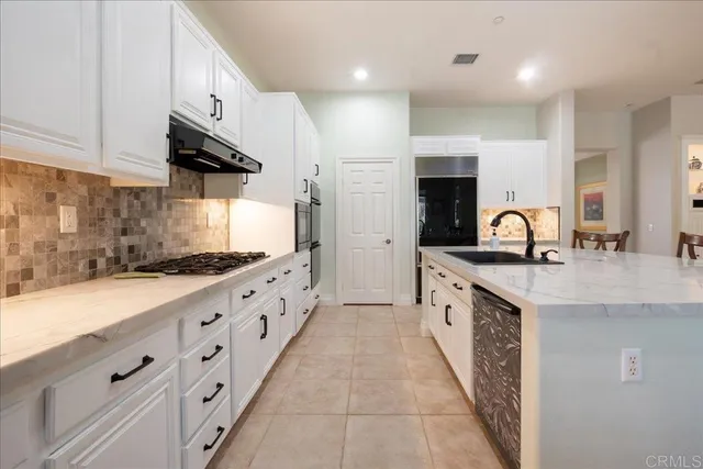 a large white kitchen with a large window and cabinets