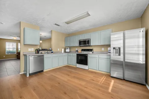 a kitchen with white cabinets stainless steel appliances and window