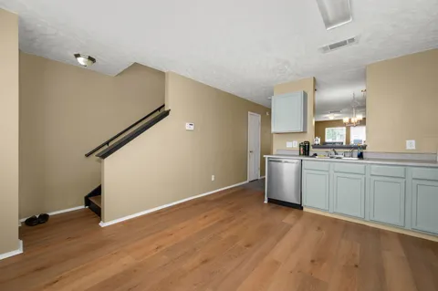 a kitchen with white cabinets and wooden floor