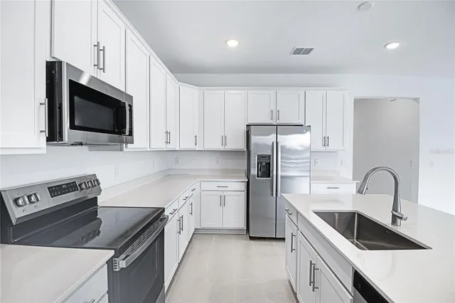 a kitchen with stainless steel appliances granite countertop a sink stove a refrigerator and microwave