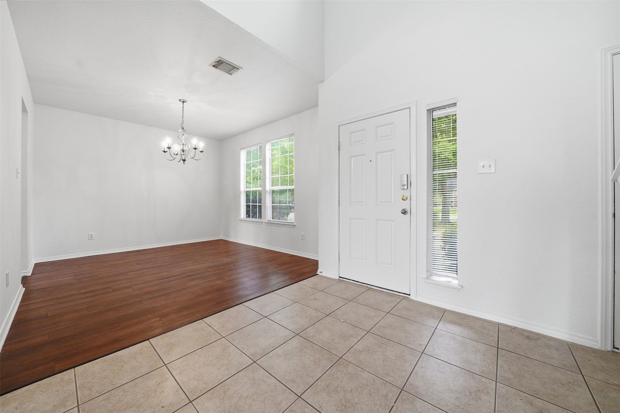 118 Invierno Street Kyle, TX 78640 - Photo 3 of 37 A welcoming entryway with tile flooring transitions to rich hardwood, illuminated by a classic chandelier.