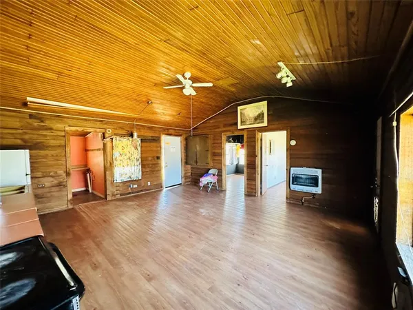 a view of an empty room with wooden floor and windows