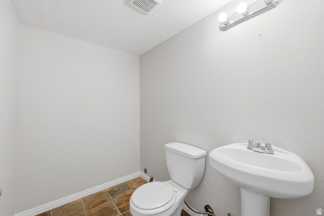 2575 Athena Drive Magna, UT 84044 - Photo 14 of 23 Bathroom featuring neutral wall paint, a white pedestal sink, a white two-piece toilet, and multi-toned tile flooring