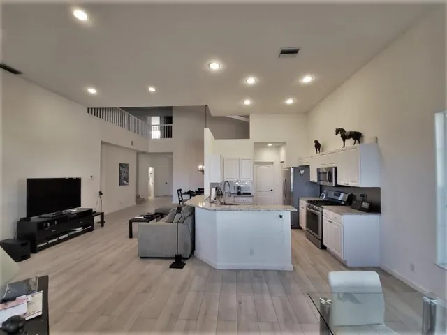 a living room with stainless steel appliances furniture and a flat screen tv