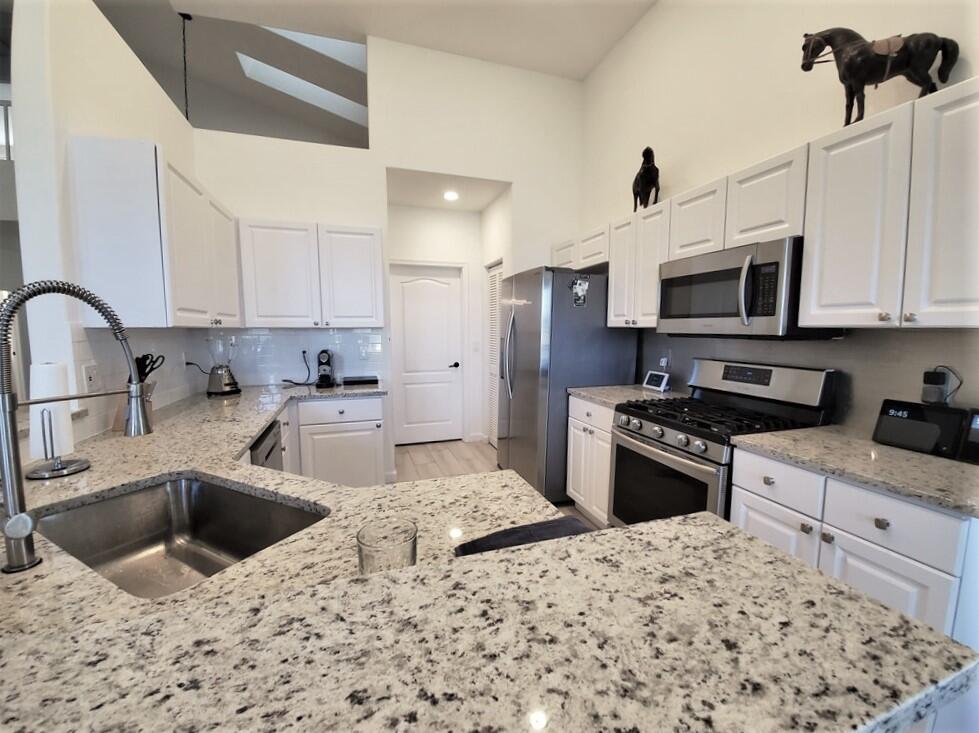 46 Pinnacle Cove Palm Beach Gardens, FL 33418 - Photo 4 of 20 a kitchen with stainless steel appliances kitchen island granite countertop a sink stove and refrigerator