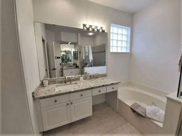 a bathroom with a granite countertop sink a large mirror and a bathtub
