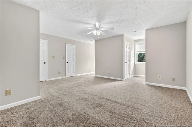 an empty room with closet and a ceiling fan