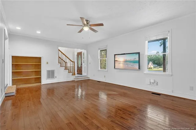a view of an empty room with a window and wooden floor