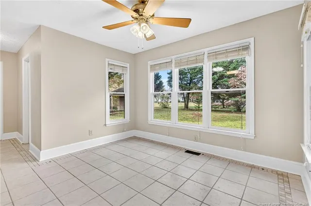 an empty room with windows and chandelier fan