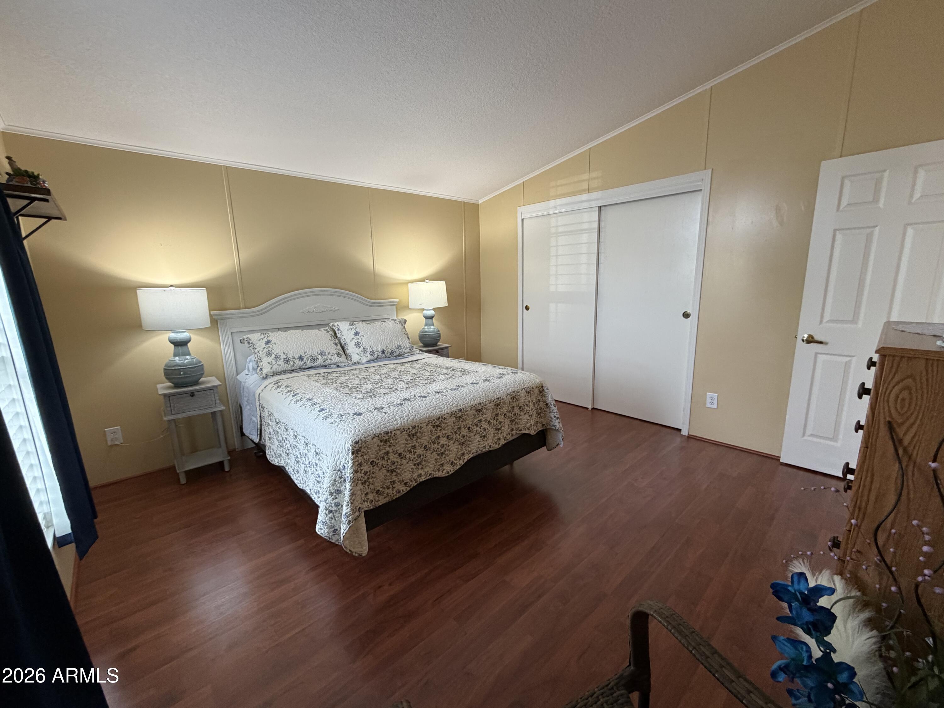 215 North Power Road, Unit 384 Mesa, AZ 85205 - Photo 16 of 27 a bedroom with a bed potted plant on dresser and a wooden floor