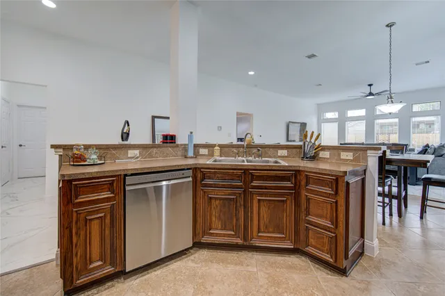 a kitchen with kitchen island granite countertop a sink cabinets and stainless steel appliances