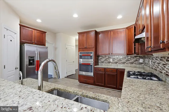 a kitchen with stainless steel appliances granite countertop a stove a sink and a refrigerator