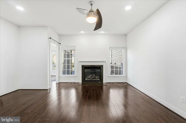 a view of an empty room with wooden floor fireplace and a window