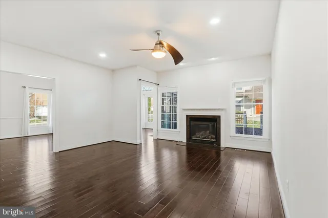 a view of an empty room with wooden floor and a ceiling fan
