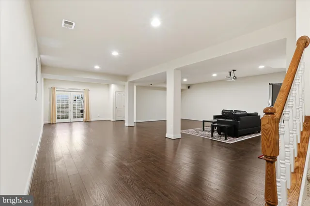 a view of an empty room with wooden floor and a kitchen