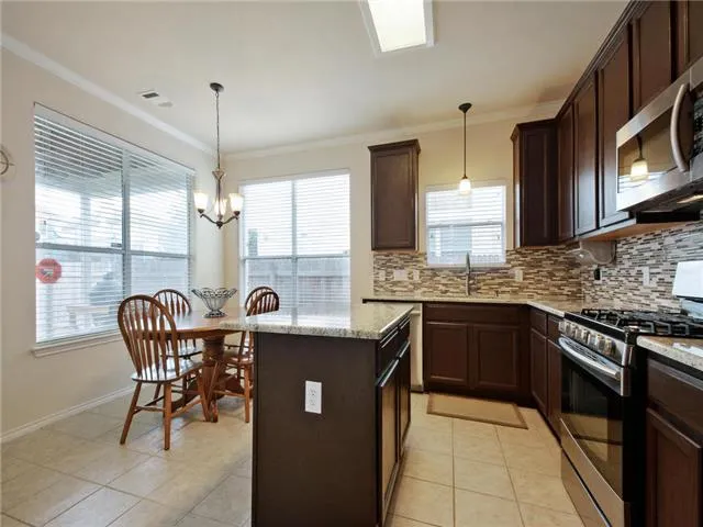 a kitchen with stainless steel appliances granite countertop a sink a stove a table and chairs