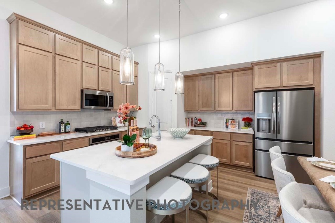 5331 Murillo Drive Manvel, TX 77578 - Photo 2 of 20 a kitchen with stainless steel appliances granite countertop a stove a refrigerator a sink dishwasher a dining table and chairs with wooden floor